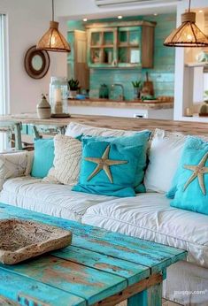 a living room filled with lots of furniture next to an ocean themed kitchen and dining area