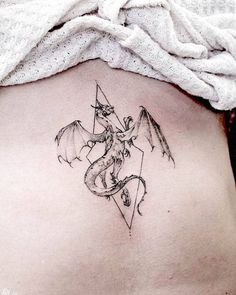 a woman with a tattoo on her stomach has a dragon and arrow behind her back