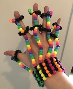 a person's hand is covered with multicolored beads and black plastic rings