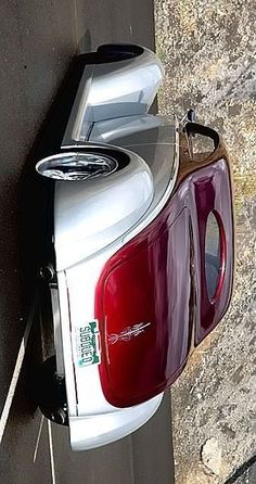 the back end of a white car parked next to a wall