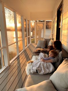 a woman and child sitting on a porch with the sun shining through the windows behind them