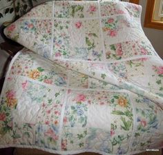 a quilted bed with flowers on it and a mirror in the corner behind it