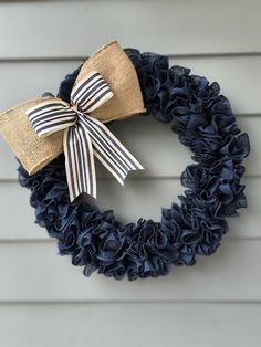 a burlock wreath with blue and white ribbon hanging on the side of a house