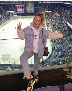 a woman standing on the edge of an ice rink with her hands in the air