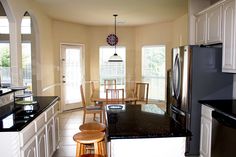 a kitchen with black counter tops and white cabinetry, along with wooden stools