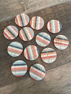 six wooden buttons with different colors on them sitting on a table next to a pair of scissors