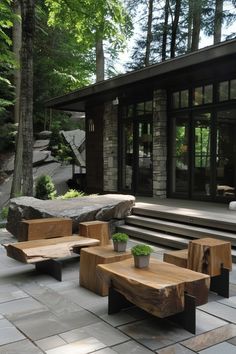 wooden benches sitting on top of a stone patio next to a tree filled forest with lots of trees