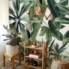 a living room with large green leaves on the wall and two stools in front of it