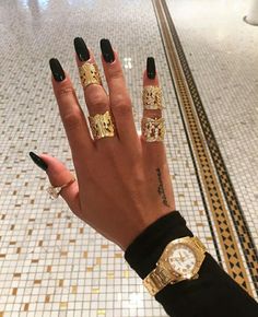 a person with black nails and gold rings