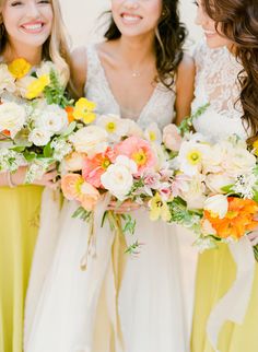 three bridesmaids in yellow dresses holding their bouquets