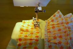 the sewing machine is on top of the yellow fabric with red and white flowered designs