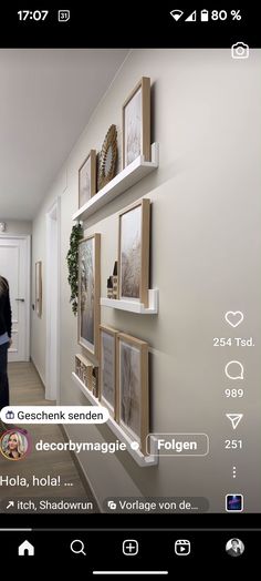 a woman standing in front of a wall with pictures hanging on the side of it