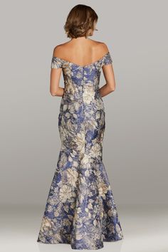 a woman in a blue and white floral print evening gown with off the shoulder sleeves