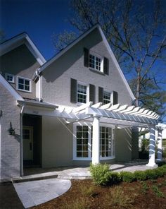 a house with a white pergolan attached to it's front door and windows