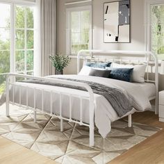 a white bed sitting in a bedroom on top of a hard wood floor next to a window