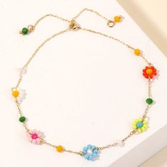 a bracelet with colorful beads and flowers on the clasp is sitting on a white surface