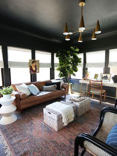 a living room filled with lots of furniture and plants on top of a carpeted floor