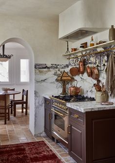 a kitchen with marble counter tops and brown cabinets, an archway leading to the dining room