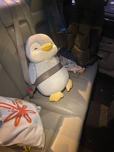 a stuffed penguin sitting in the back seat of a car