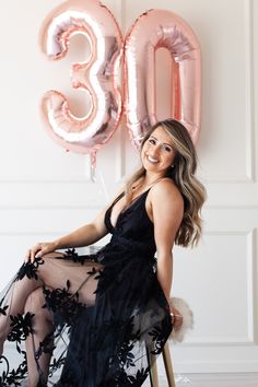 a woman sitting on a chair in front of a balloon and the number 30 sign