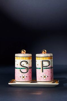 two salt and pepper shakers on a tray with the letter s painted on them