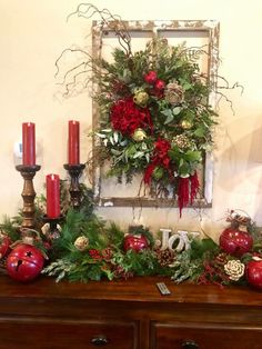 a christmas mantle decorated with red and green decorations, pine cones, greenery, candles and pomegranates