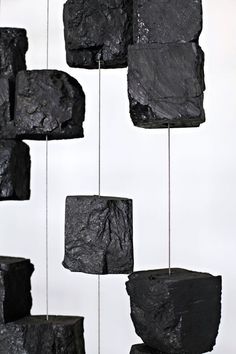 some black rocks hanging from strings on a white wall