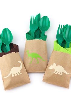 four green plastic utensils in small bags with dinosaurs on them