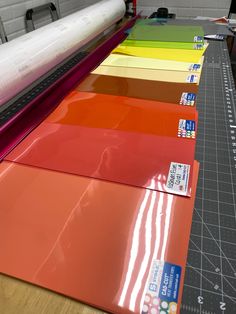 several different colors of paper on a table with a large machine in the back ground