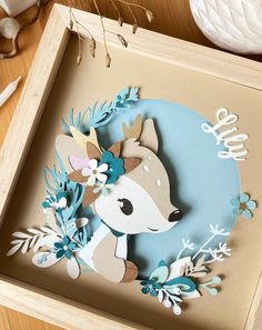 a paper cut out of a deer with flowers on it's head in a box