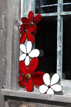 a red and white stained glass flower on a window sill