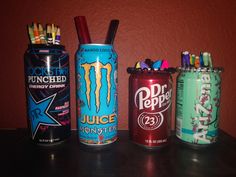 four cans are lined up next to each other on a table with pens and pencils in them