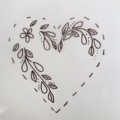 a heart made out of flowers and leaves on a white plate with the words love written in it