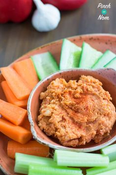 carrots and celery are in a bowl on a plate with the dip