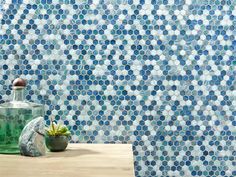 a table topped with a bottle filled with liquid next to a wall covered in hexagonal tiles