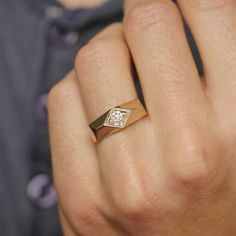 a close up of a person's hand wearing a gold ring with a diamond