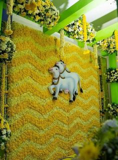 a white horse is standing in the middle of yellow and green wallpaper with flowers hanging from it's sides