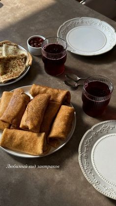 some food is sitting on a table with plates and cups next to it that have sauces in them