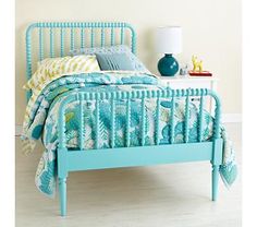 a bed with blue headboard and foot board next to a lamp on a table