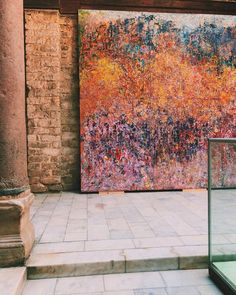 an abstract painting on display in front of a brick building with steps leading up to it