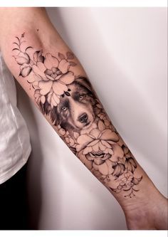 a woman's arm with flowers on it and a dog in the middle,