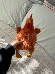 a person holding a stuffed chicken on top of a bed