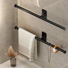 two black towel racks in a bathroom next to a wall mounted toilet paper dispenser