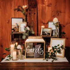 a table topped with framed pictures and flowers on top of a wooden table next to candles