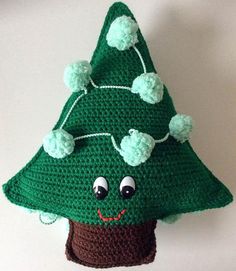 a crocheted green christmas tree ornament hanging from a hook on a wall