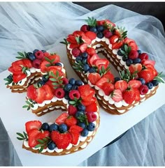 three cakes decorated with strawberries, blueberries and raspberries on top of each other