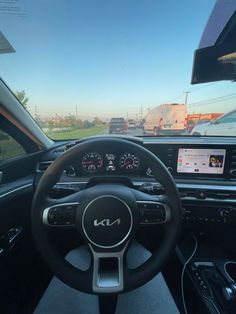 the interior of a car with steering wheel, dashboard and display screen showing cars driving on a highway