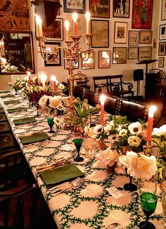 a long table is set with green and white placemats, candles, and pictures on the wall