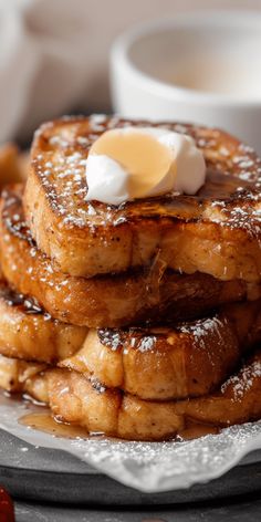 a stack of pancakes covered in powdered sugar and topped with butter on a plate