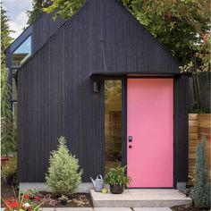 a pink door in front of a black house